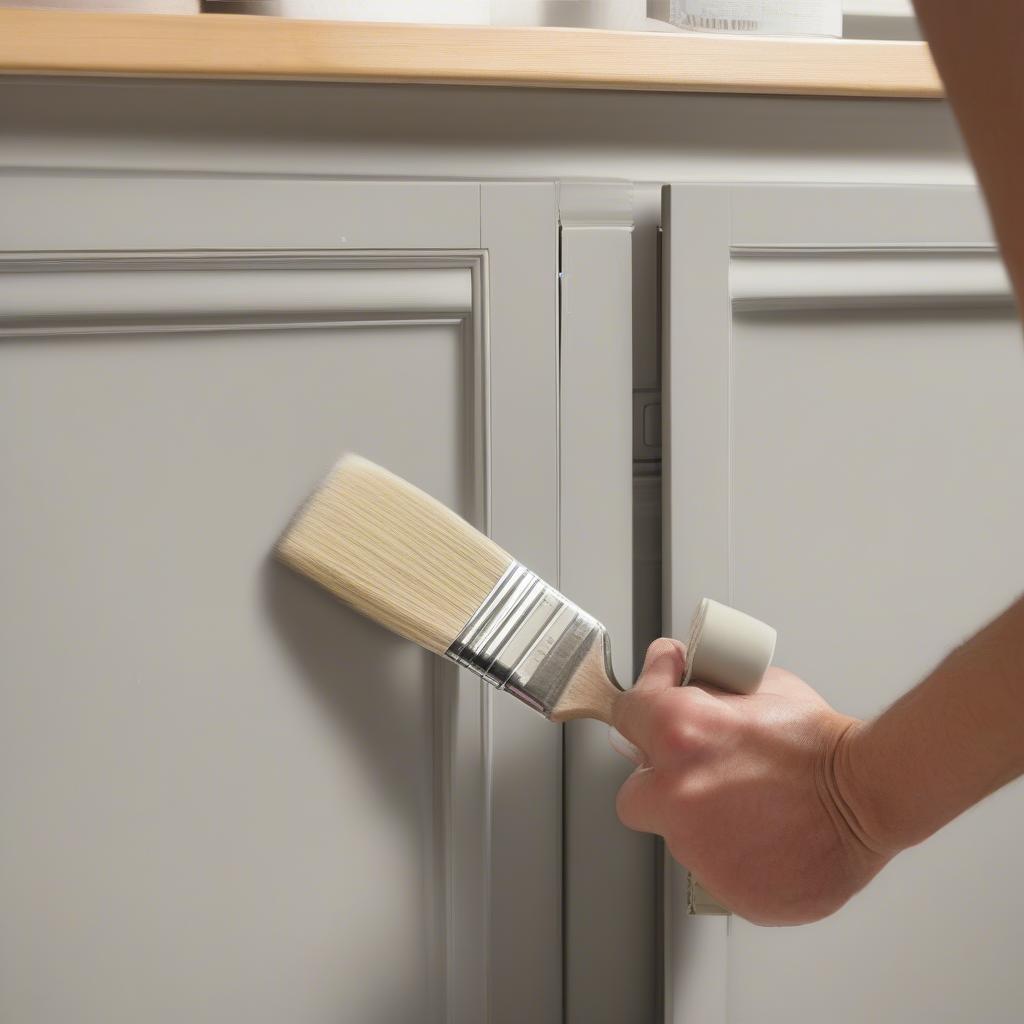 Applying Wickes kitchen cabinet paint using a brush and roller.