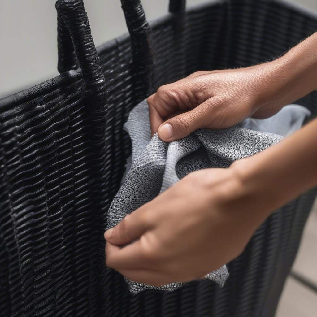 Cleaning a resin wicker tote with a damp cloth.