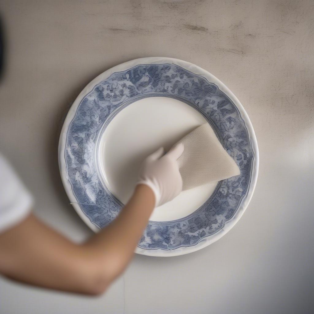 Cleaning ceramic wall plates with a soft, dry cloth to maintain their beauty.