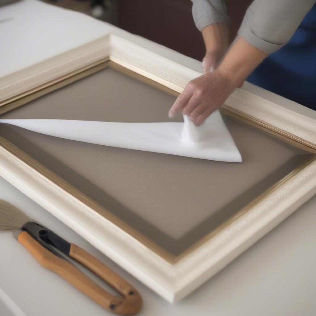 Close-up of a hand gently dusting a 24x36 matted picture frame with a soft cloth, demonstrating proper cleaning techniques.