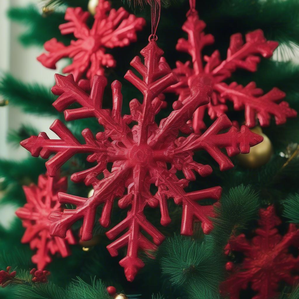 Red snowflake ornaments hanging on a Christmas tree